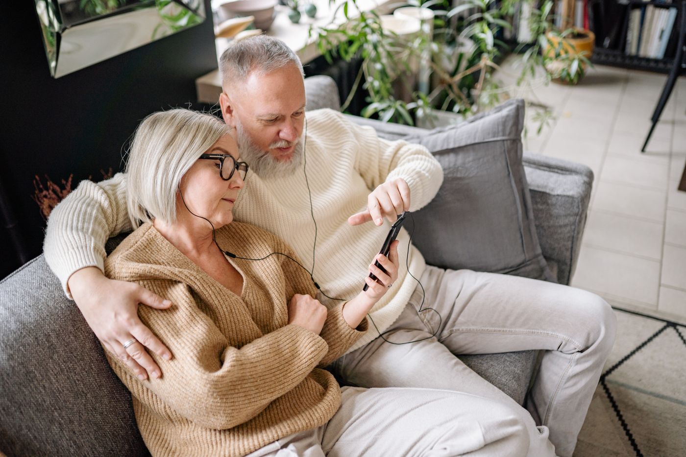 A couple on the sofa listening to a phone with shared earphones